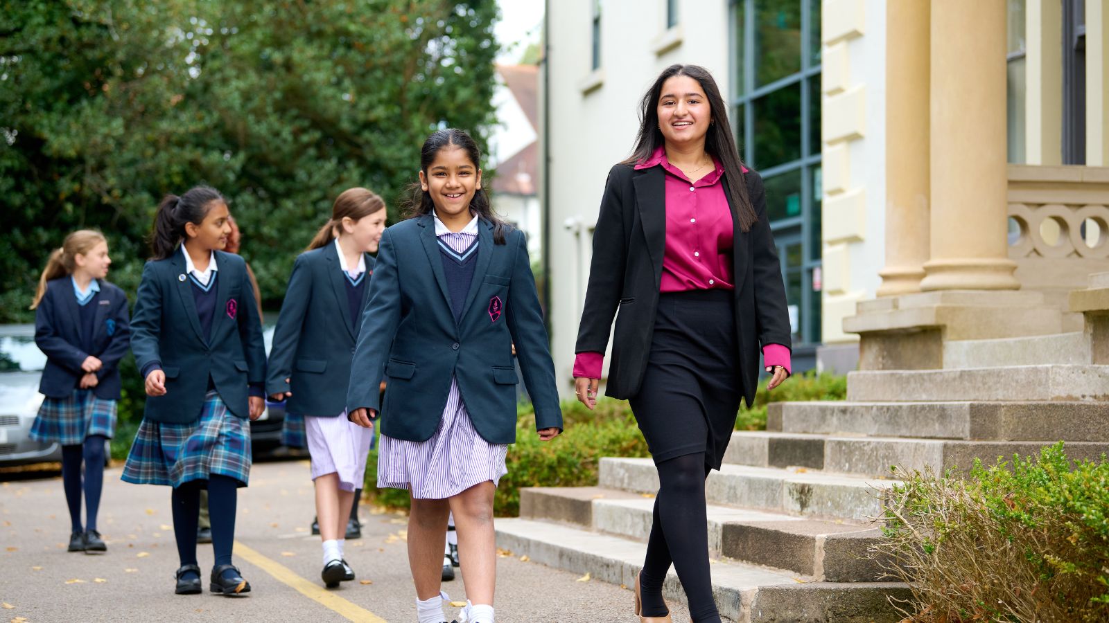 a group of students of different ages walking past a building